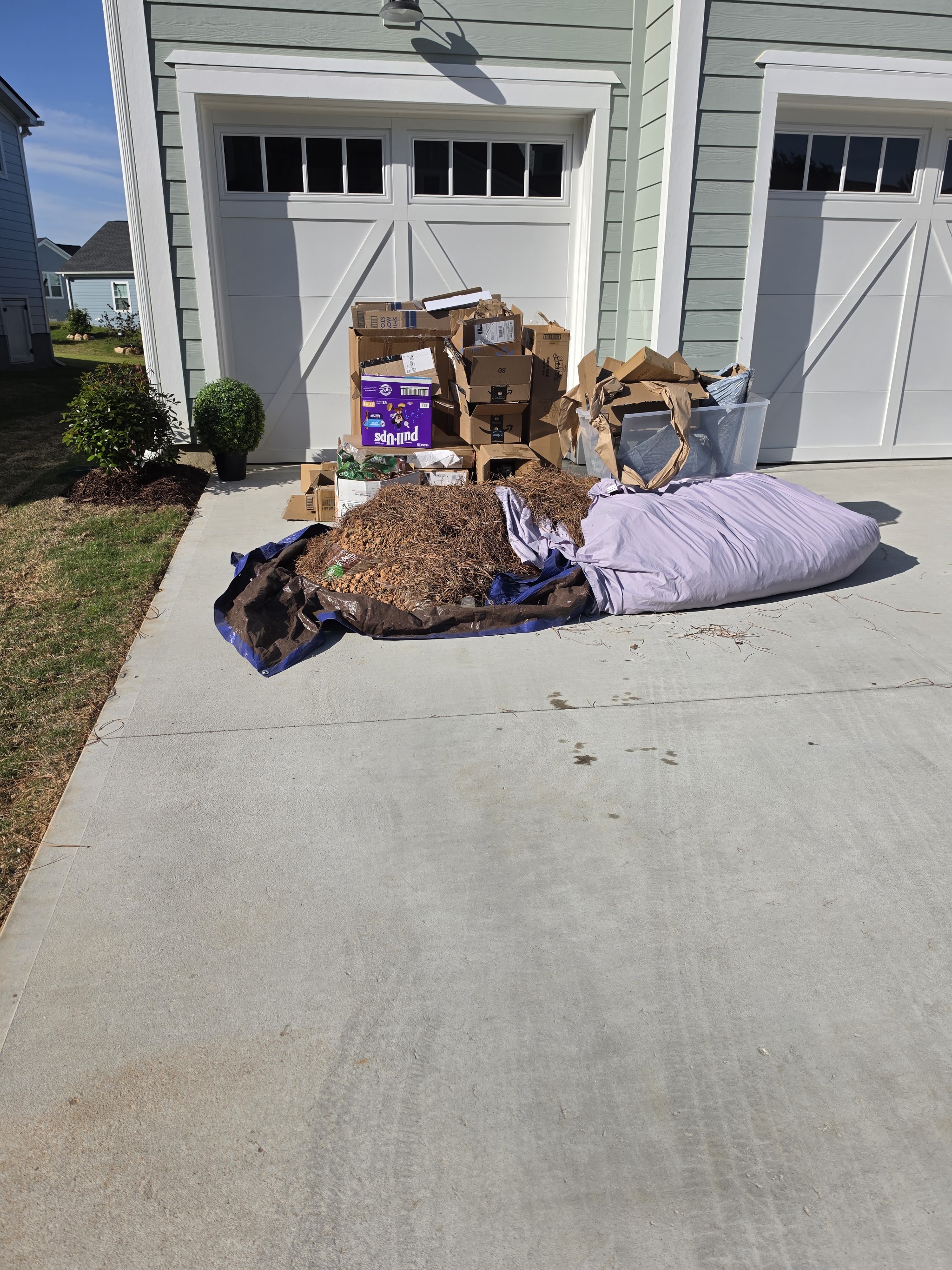 A pile of boxes, bedding and junk on a driveway waiting for pick up
