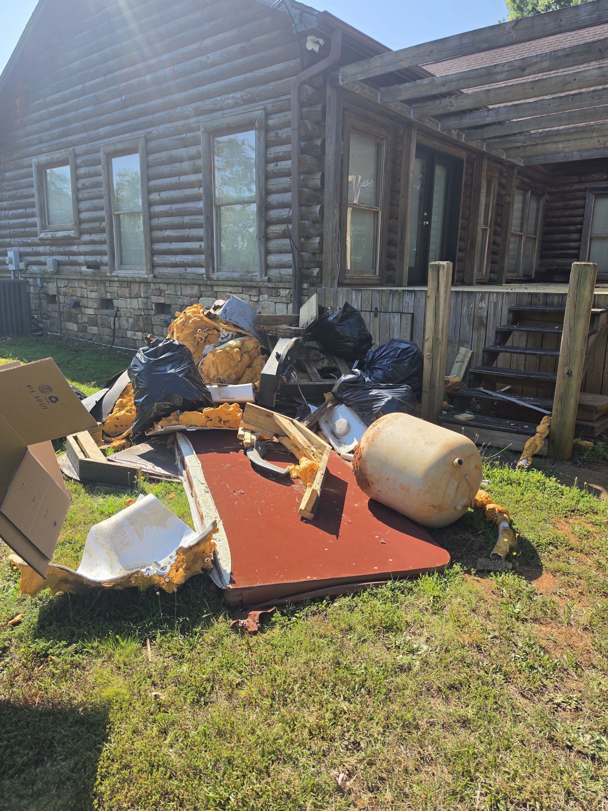 Boxes, bags and a pile of junk beside a porch before pick up